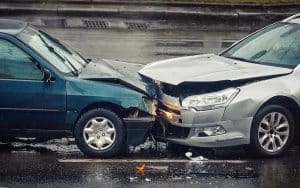 Two cars involved in a front-end collision on a wet road, illustrating the aftermath of a car accident, relevant to types of car accidents and legal considerations.